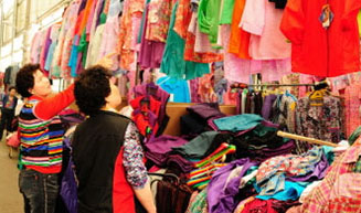 서시장 내부의 옷가게에서 진열된 옷들을 구매하기위해 살펴보는 구매자들