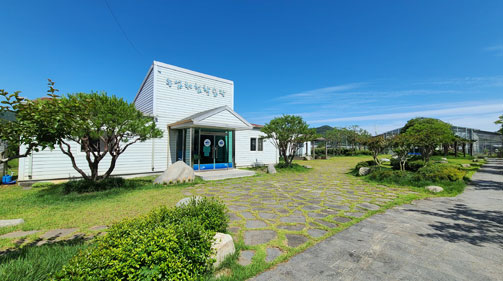 파란 하늘 아래 잔디밭과 나무가 있고 농업인체험학습장 건물이 있다