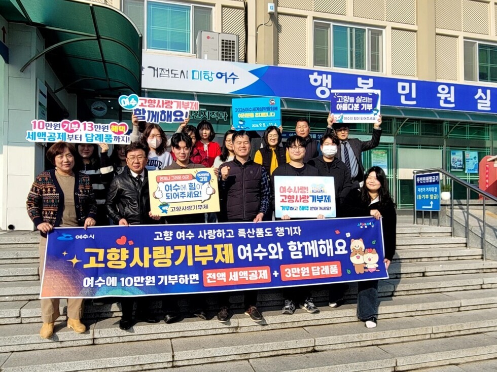 여수시에서 고향사랑기부제를 홍보하는 행사로, 여러 사람들이 현수막을 들고 기부를 독려하고 있다.