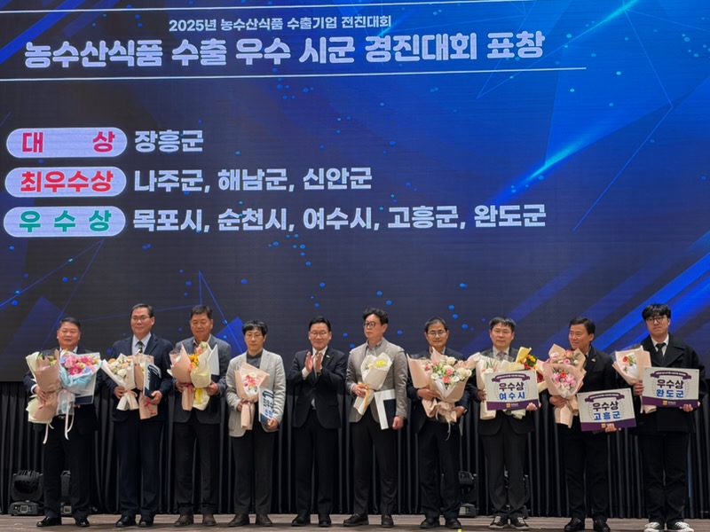 2025년 농수산식품 수출기업 전진대회 시상식 현장에서 수상자들이 무대에 서서 꽃다발과 상장을 들고 기념촬영을 하는 모습. 배경 화면에는 대상 장흥군, 최우수상 나주군·해남군·신안군, 우수상 목포시·순천시·여수시·고흥군·완도군이 표시되어 있다.