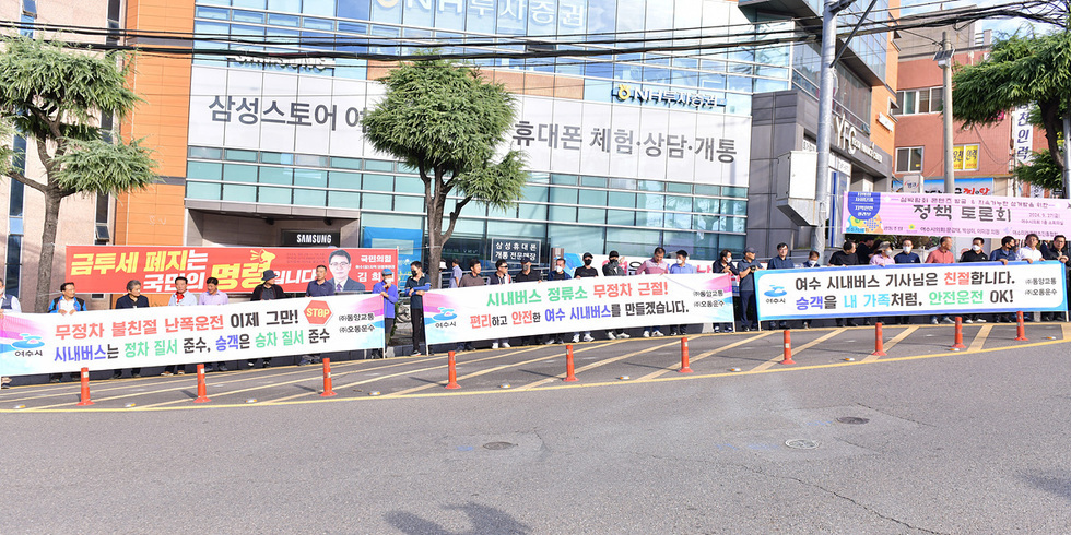 여수에서 시내버스 정류소 무정차 근절을 요구하는 시민들이 집회를 열고 있다. 여러 개의 현수막이 걸려 있으며, 시민들이 시위에 참여하고 있다.