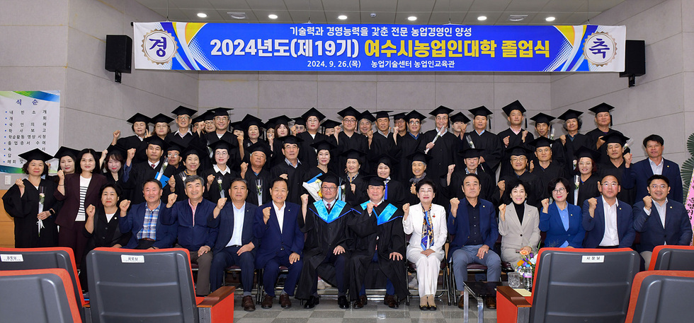 2024년도 여수시농업인대학 졸업식에서 졸업생들이 모여 기념사진을 찍고 있다. 졸업생들은 학사모를 쓰고 있으며, 배경에는 졸업식 관련 현수막이 걸려 있다.