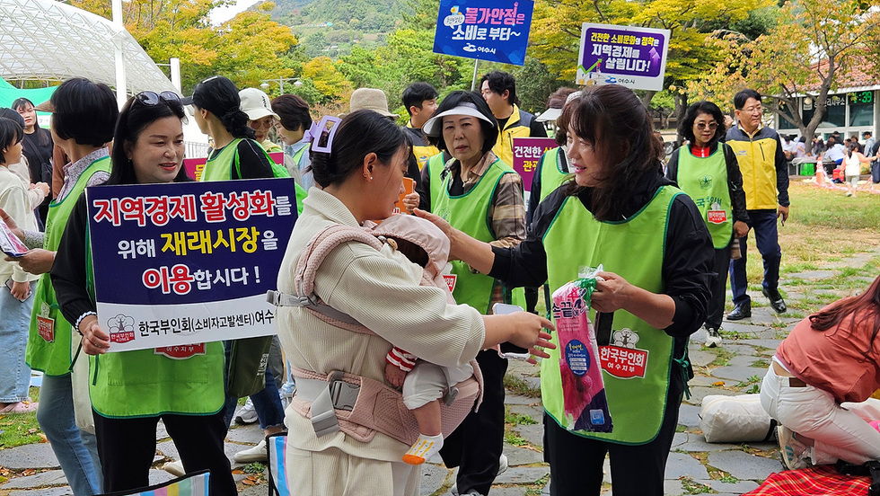 여수에서 지역경제 활성화를 위한 재래시장 이용을 촉구하는 행사에서 참가자들이 물품을 나누고 있다.