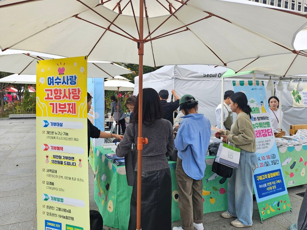 여수사랑 고향사랑 기부제를 알리는 현수막이 있는 행사에서 사람들이 기부를 위해 대기하고 있다.