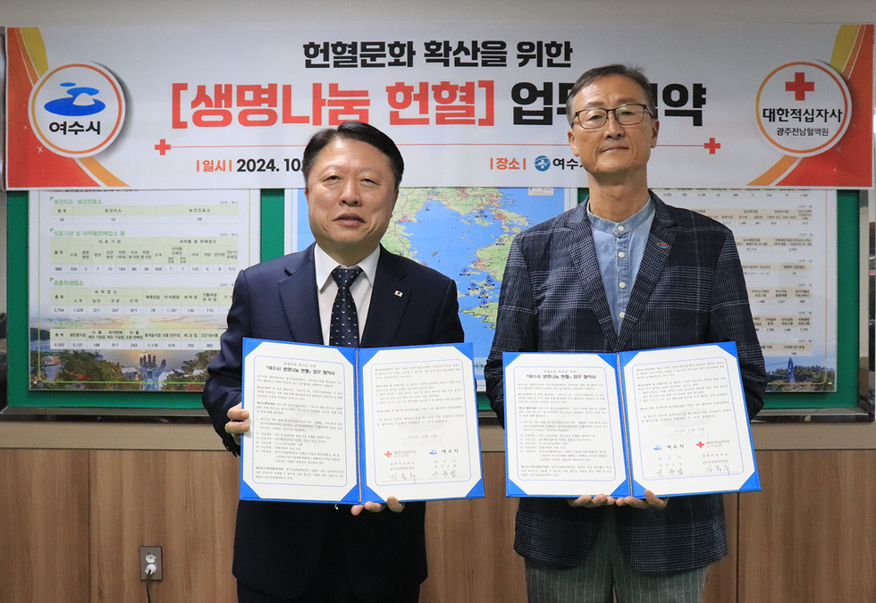 여수시에서 생명나눔 헌혈 업무협약을 체결하는 장면으로, 두 사람이 협약서를 들고 서 있다.