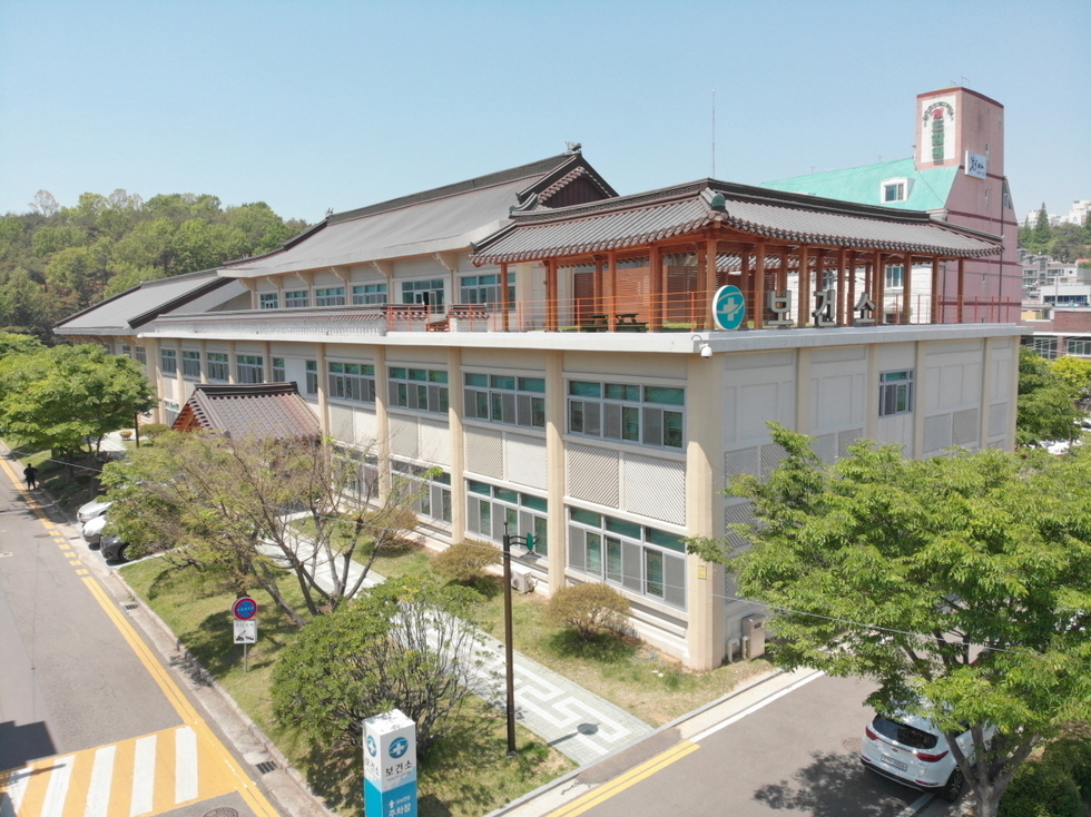 환경소 건물이 보이는 장면으로, 주변에 나무와 도로가 있으며 차량이 주차되어 있다.