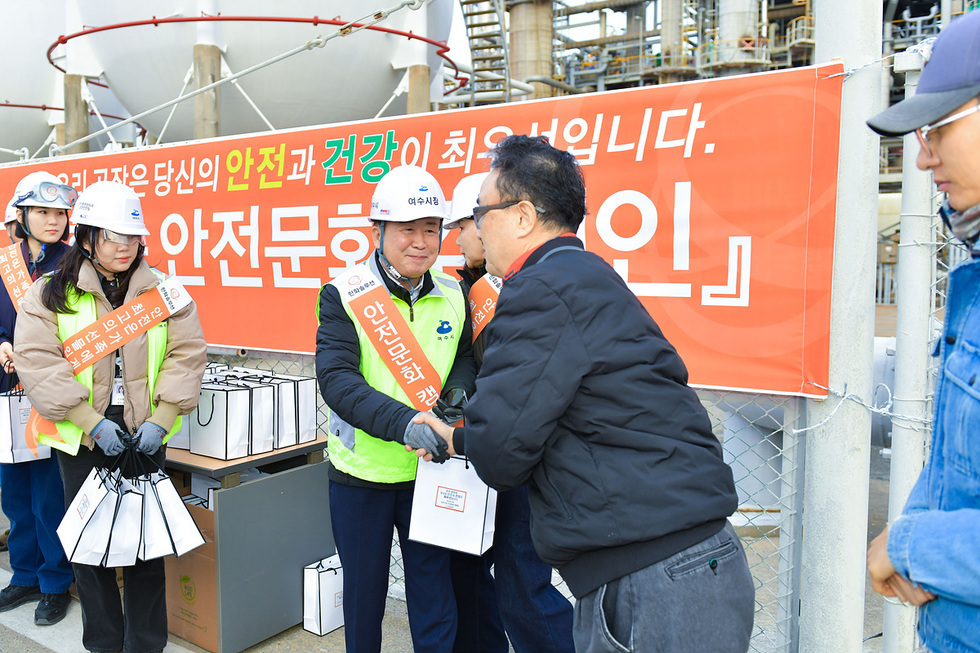 안전문화 캠페인 행사에서 참가자들이 인사를 나누고 있으며, 배경에는 안전과 건강을 강조하는 현수막이 걸려 있다.