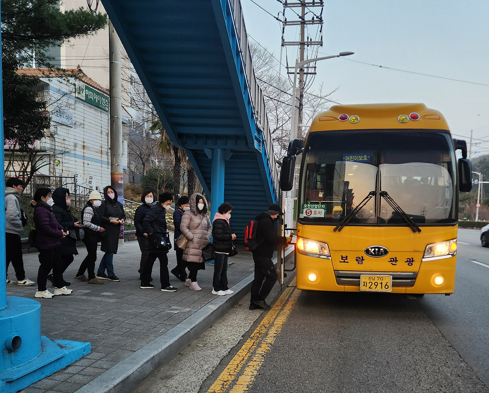 보람관광 버스가 정차해 있고, 승객들이 버스에 탑승하기 위해 줄을 서 있는 모습이다.
