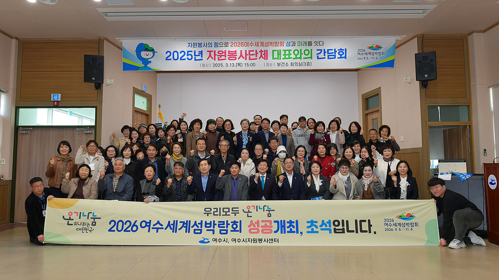 2025년 자원봉사단체 대표와의 간담회가 진행되고 있는 모습으로, 참석자들이 단체 사진을 찍고 있다. 배경에는 2026 여수세계섬박람회 성공개최를 기원하는 현수막이 걸려 있다.
