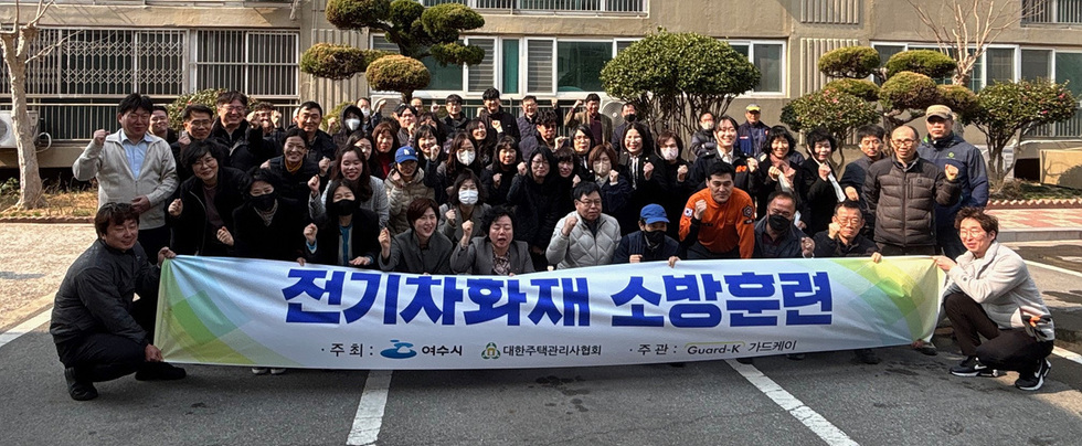 여수시에서 전기차 화재 소방훈련을 위해 모인 참가자들이 현수막 앞에서 포즈를 취하고 있다.