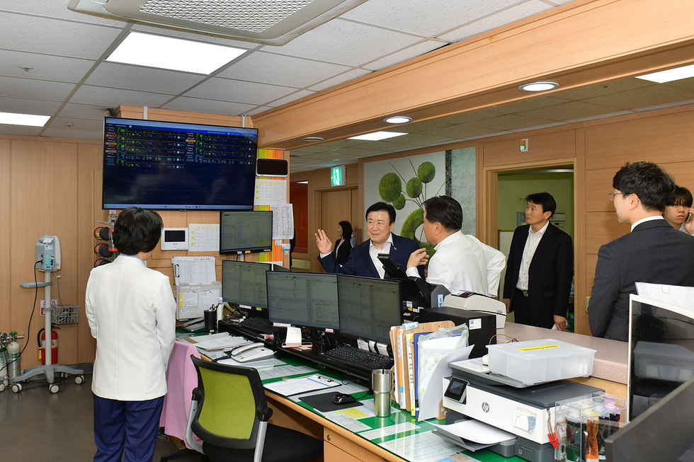 의료진과 관계자들이 병원 사무실에서 대화하고 있으며, 모니터에는 환자 정보가 표시되고 있다.