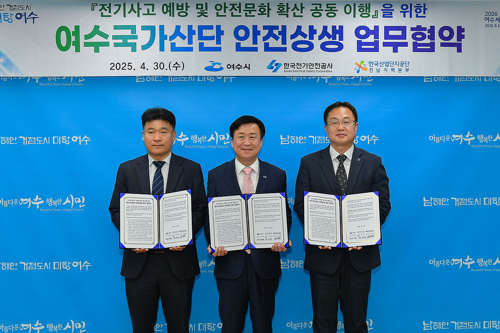 여수시에서 여수국가산단 안전상생 업무협약을 체결하는 장면으로, 세 명의 남성이 협약서를 들고 서 있다.