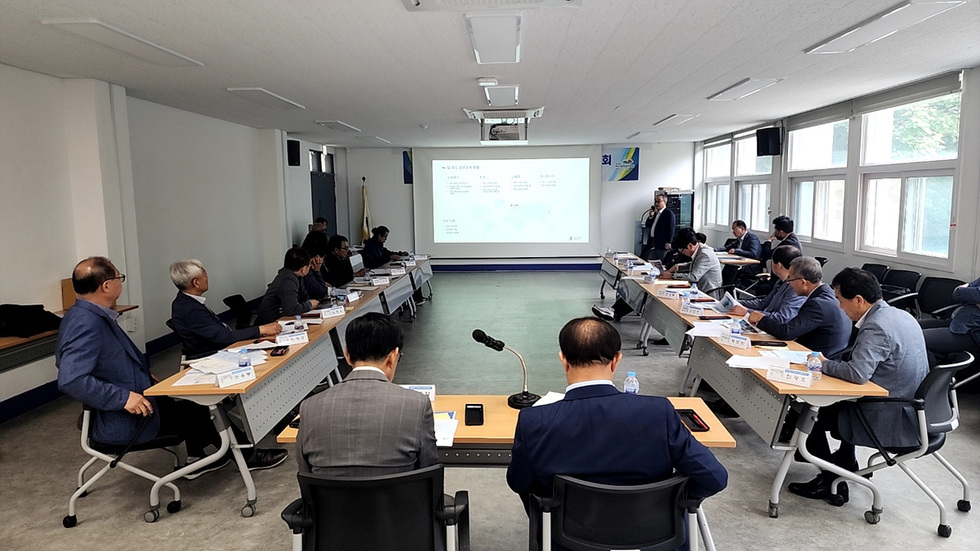 회의실에서 여러 명의 참석자들이 회의에 참여하고 있으며, 화면에는 발표 내용이 표시되고 있다.
