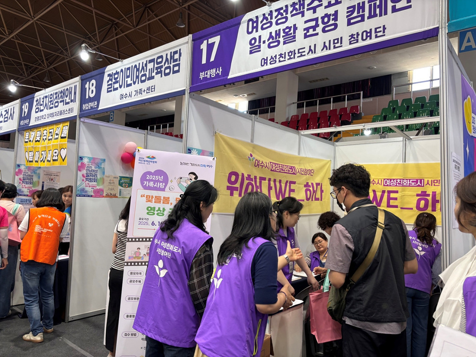 여성친화도시 시민참여단이 부스에서 일생활 균형 캠페인에 대해 설명하고 있으며, 참가자들이 정보를 교환하고 있다.