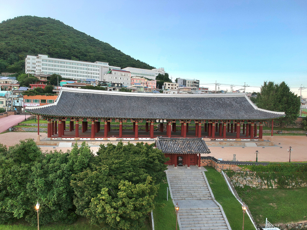 여수 진남관의 전경이 담긴 사진으로, 복원된 전통 건축물이 보이고 주변에 나무와 산이 있다.