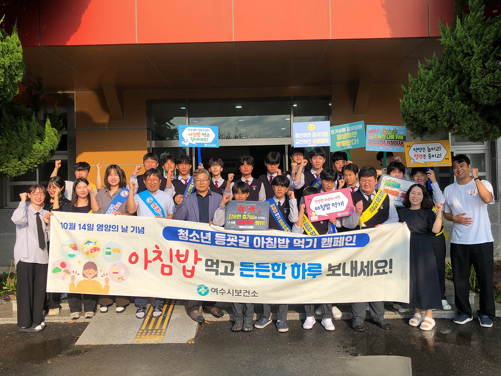 여수시에서 아침밥 먹기 캠페인에 참여한 시민과 학생들이 10월 14일 영야의 날 기념 청소년 등굣길 아침밥 먹기 캠페인 아침밥먹고 든든한 하루 보내세요!현수막을 들고 포즈를 취하고 있다