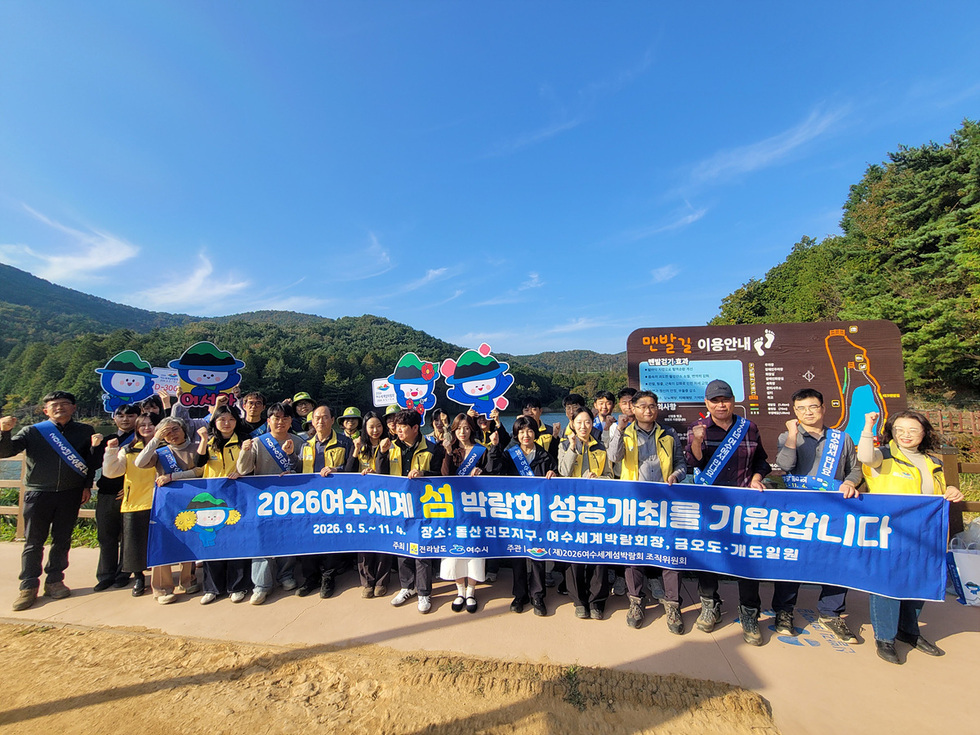 봉화산 산림욕장에서 여수시와 산림단체 관계자들이 ‘2026여수세계섬박람회 성공개최를 기원합니다(2026.9.5.~11.4)’라는 문구가 적힌 파란색 현수막을 들고 기념 촬영하는 모습