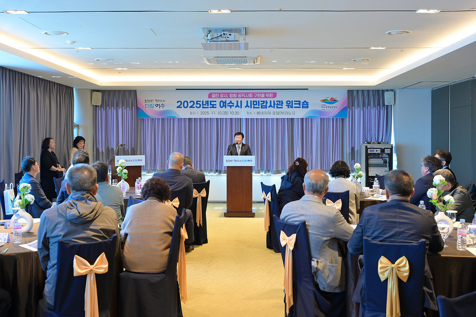 여수시 시민감사관 워크숍 행사장에서 정기명 여수시장이 단상에서 인사말을 하고 있는 모습. 회의실에는 시민감사관들이 테이블에 앉아 강연을 경청하고 있다. 배너에는 ‘2025년도 여수시 시민감사관 워크숍’ 문구가 보인다.