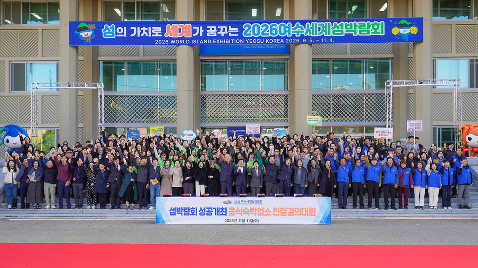 2026여수세계섬박람회 성공개최를 위한 결의대회에 참가한 여수시 음식·숙박업소 관계자들이 시청 앞에서 손을 들고 구호를 외치고 있는 모습. 건물 상단에는 ‘섬의 가치로 세계가 꿈꾸는 2026여수세계섬박람회’ 현수막이 걸려 있다