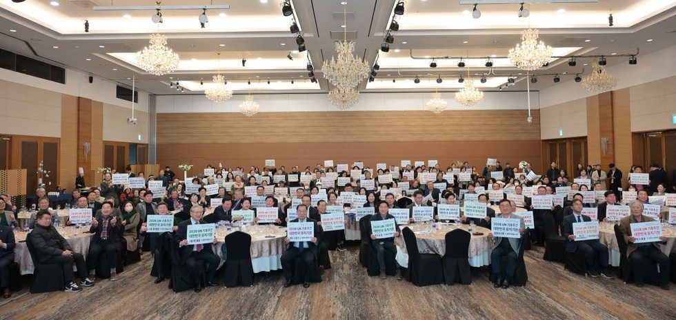 대형 연회장에 모인 참여자들이 원탁에 앉아 ‘2026 UN 기후주간 대한민국 유치 지지’ 문구가 적힌 피켓을 들고 단체로 들어 보이며 기념촬영하는 모습.