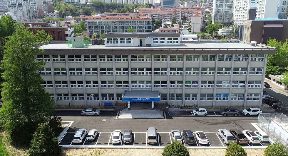 여수시청 건물의 정면 모습으로, 주차장에는 여러 대의 차량이 주차되어 있다.