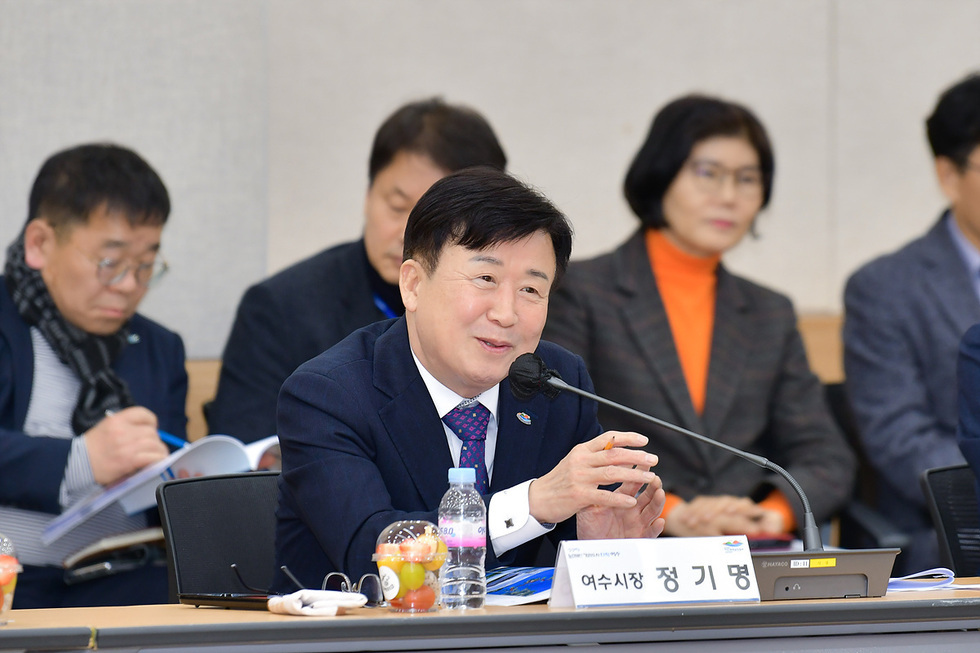 여수시장에서 정기명이 회의 중 발언하고 있으며, 배경에는 다른 참석자들이 앉아 있다.