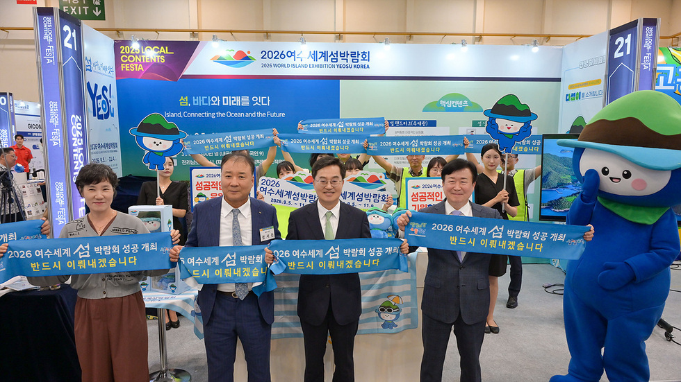 2026여수세계섬박람회 홍보 부스에서 관계자들이 성공 개최를 다짐하는 현수막을 들고 기념 촬영하는 모습