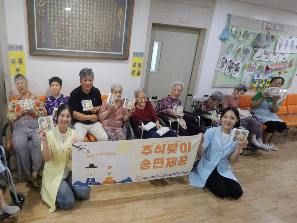 여수시에서 진행된 추석맞이 송편 제공 행사에서 사회복지시설 이용자들이 송편을 들고 기념사진을 찍고 있다.