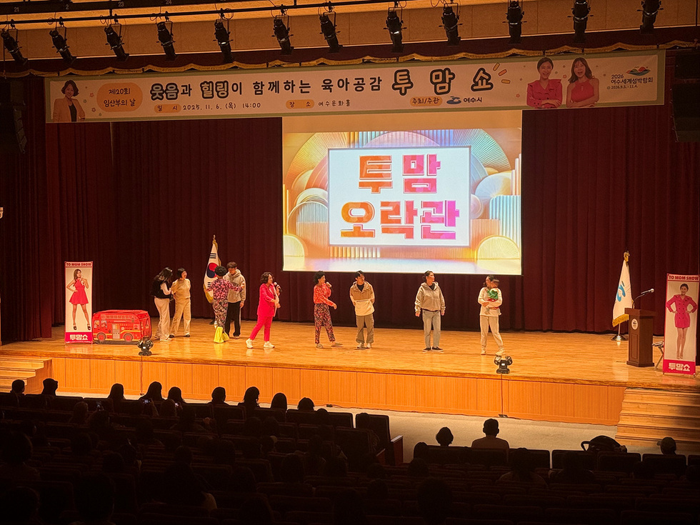 여수문화홀 무대에서 ‘제 10회 임산부의 날 웃음과 힐링이 함께하는 육아공감 투맘쇼 일시 : 2025년 11월 6일 (목) 14:00 장소 :여수문화홀 주최/주관 여수시’ 현수막 아래 개그우먼들이 ‘투맘 오락관’ 프로그램을 진행하며 관객들과 소통하는 모습