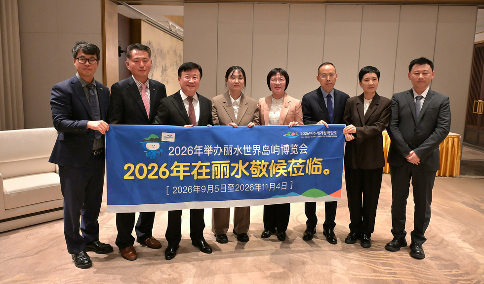 정기명 여수시장과 중국 리수이시 대표단이 함께 ‘2026년 여수세계섬박람회’ 홍보 현수막을 들고 기념촬영을 하는 모습. 현수막에는 ‘2026年在丽水敬候莅临(2026년 여수에서 기다립니다)’ 문구가 적혀 있다.